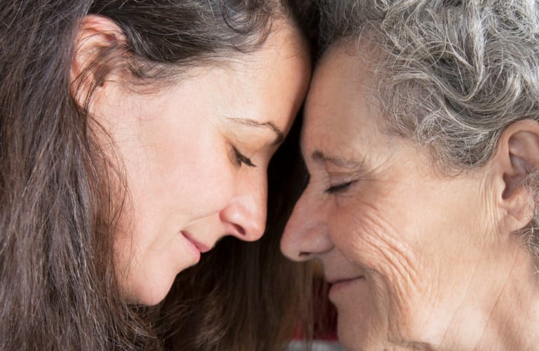 Older woman and her daughter touching foreheads with their eyes closed