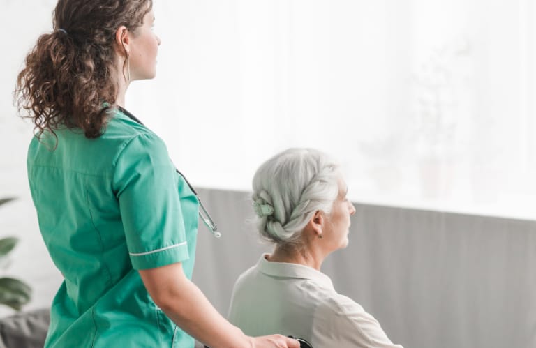 Caregiver pushing an elderly woman in a wheelchair